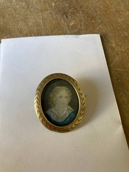 Petite broche en pomponne avec peinture sous verre bombé, d’un portrait de jeune garçon