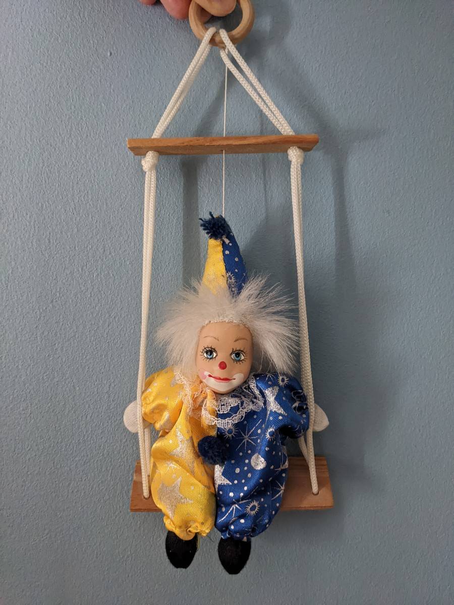 Poupée clown en porcelaine sur balançoire